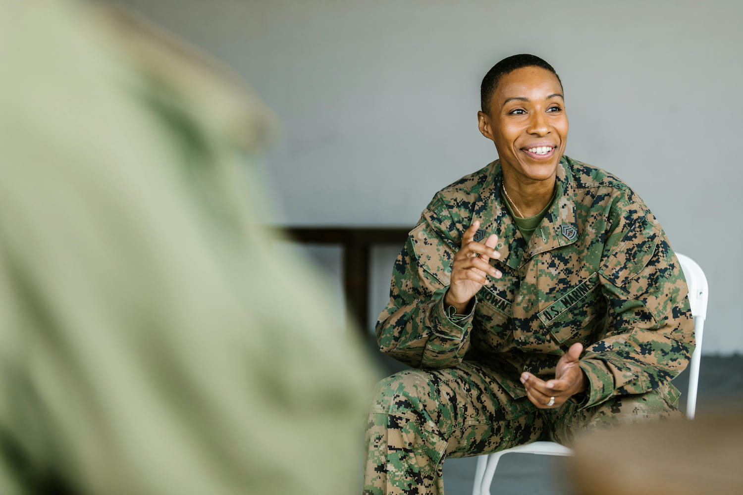  woman in fatigues sitting on white folding chair