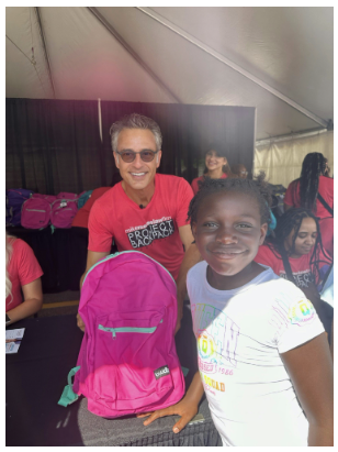 A happy Metro-Detroit student receives her a backpack filled with school supplies from Mike Morse. 