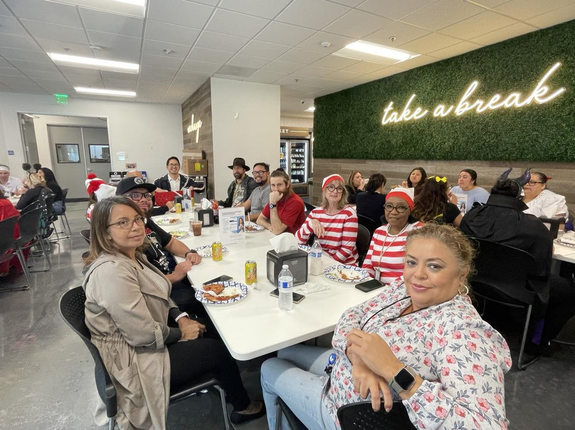 Employees enjoying Halloween celebration pizza lunch.