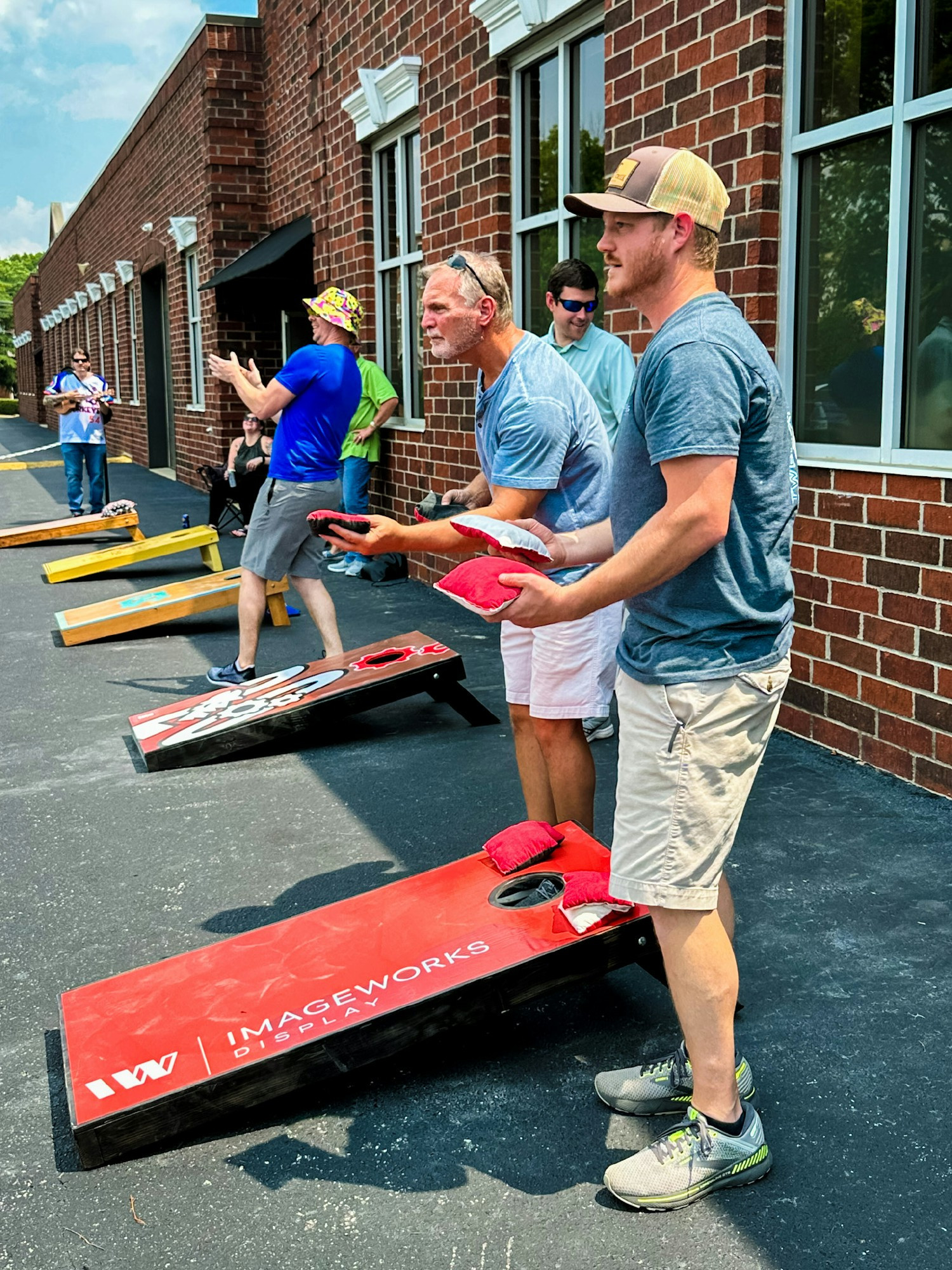 Work hard, play hard! Employees enjoying a sunny afternoon while engaging in a competitive corn hole tournament.