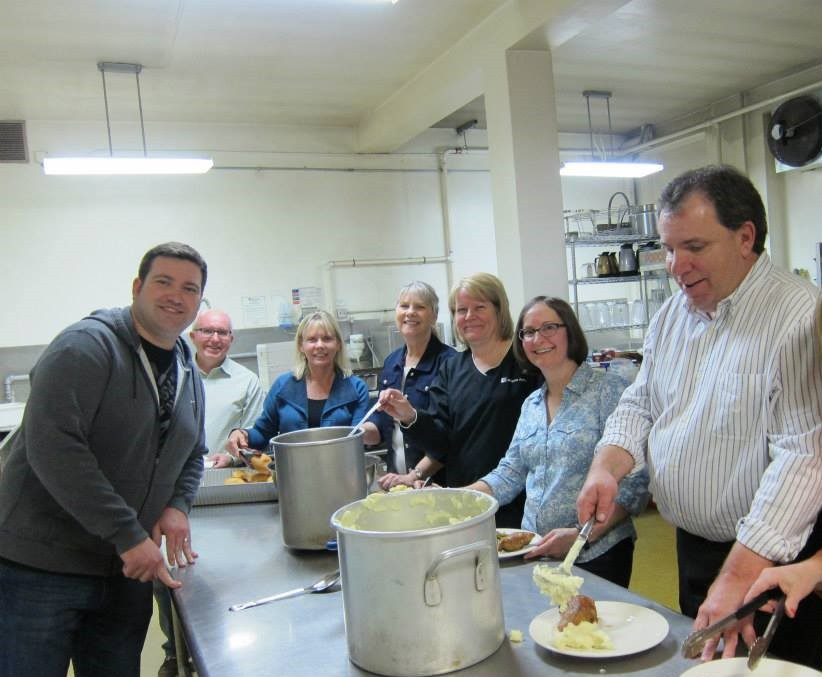 Employees volunteer to prepare and serve food at a local church