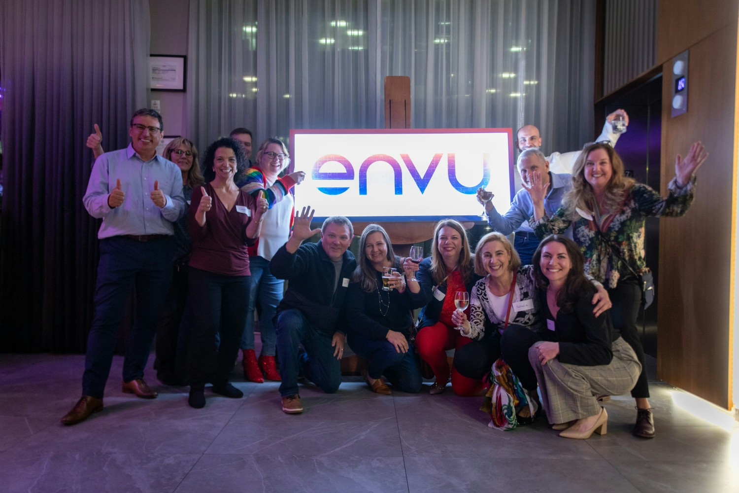 Employees gather around puzzle sign where each employee added a piece to complete the Envu logo as part of launch event.